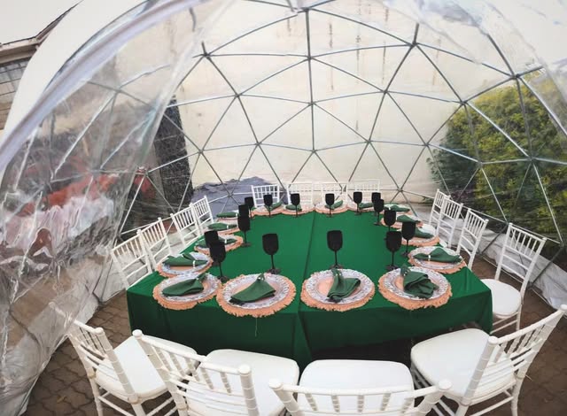 Private dinner table inside a clear dome with emerald linens